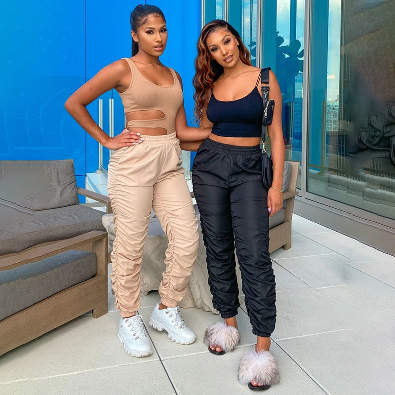 Two women posing together in stylish outfits on a rooftop with a blue wall and glass door in the background.