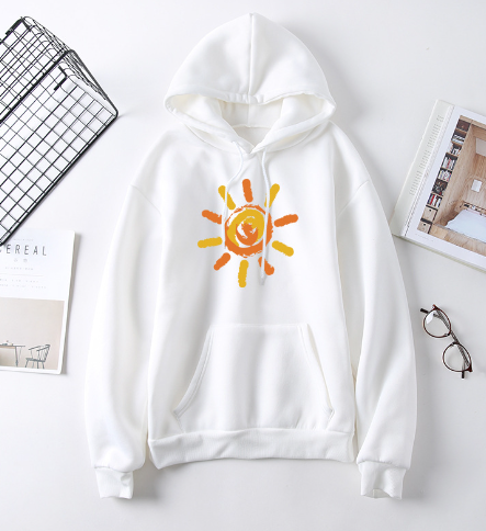 White hoodie with a sun design on a white surface with a wire basket and magazine in the background.